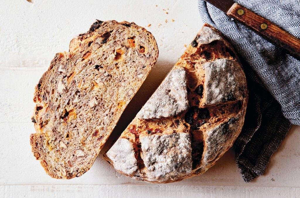 round baked loaf of No-knead showind bread cut in half to show textureharvest bread